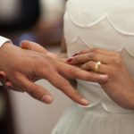 bride putting a ring on grooms hand